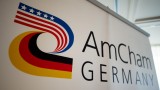 Auf einer Fotowand ist das Logo der Amerikanischen Handelskammer in Deutschland, der AmCham Germany, im Hotel "Hilton Park" in München (Bayern) zu sehen.&nbsp; (picture alliance / dpa / Inga Kjer)