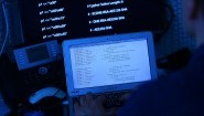 Ein Mann sitzt vor einem Rechner mit Computer Quellcode auf dem Bildschirm.&nbsp; (picture alliance /dpa / Oliver Berg)